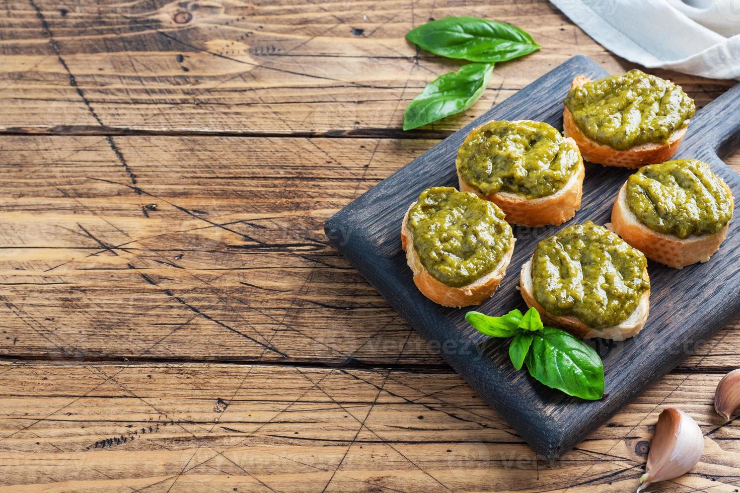 sanduíches com molho pesto, folhas de manjericão fresco e alho. um delicioso lanche saudável. fundo rústico de madeira. espaço de cópia foto