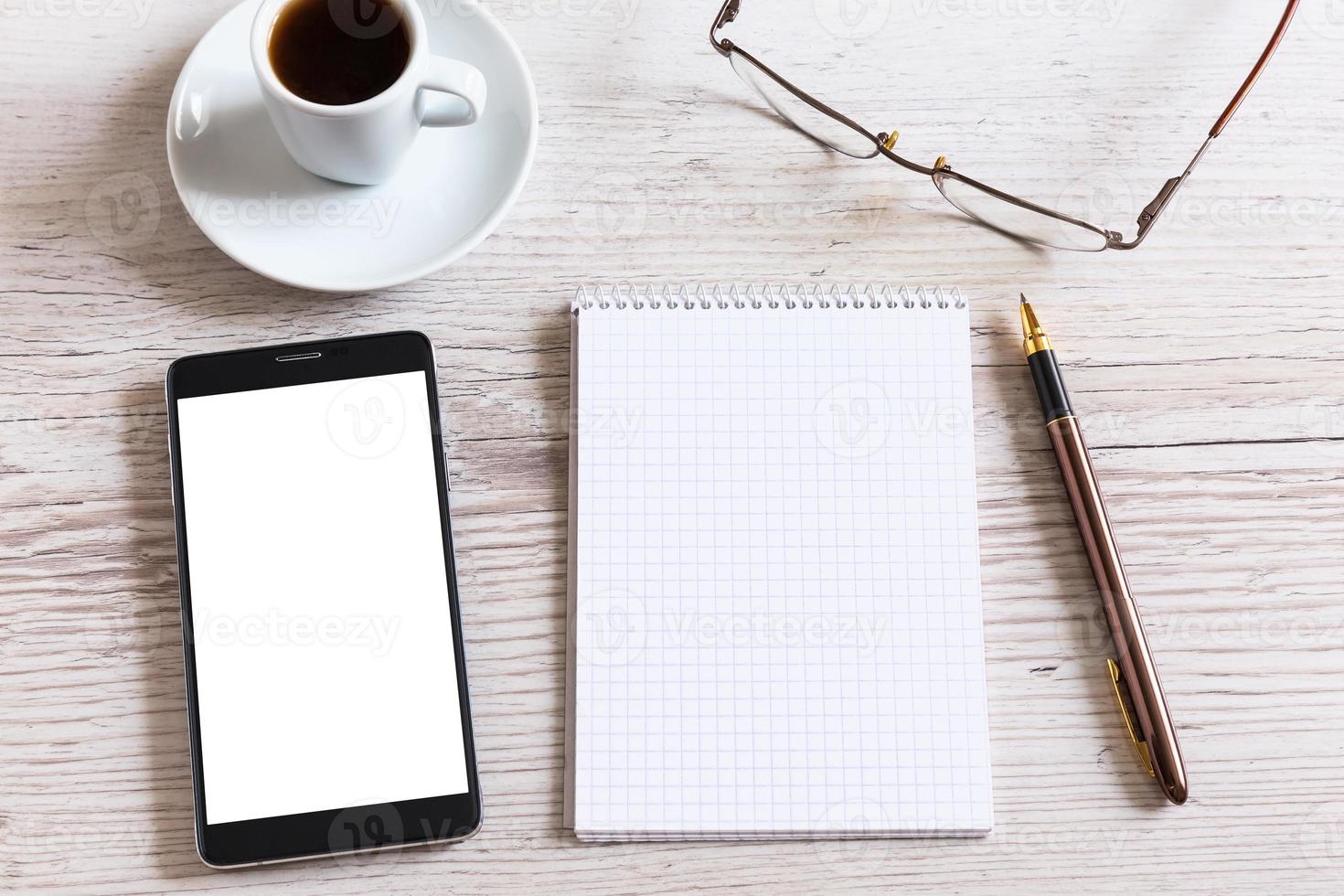 caderno com caneta, telefone inteligente e xícara de café foto