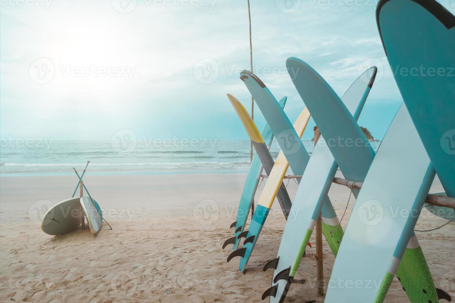 muitas pranchas de surf para alugar na praia de verão com céu azul da luz do sol. foto