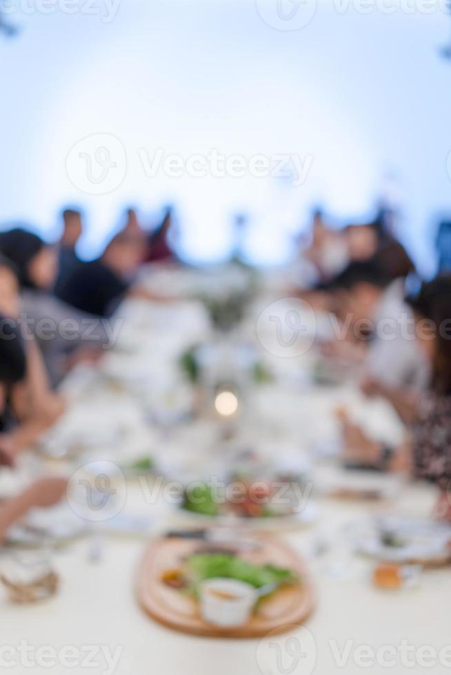 jantar embaçado com o projetor e tela branca para o público asiático sentado na longa fila da mesa. foto