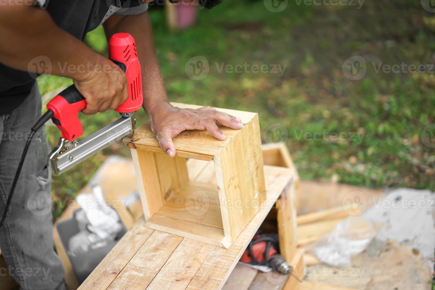 carpinteiro asiático está atirando air nailer foto