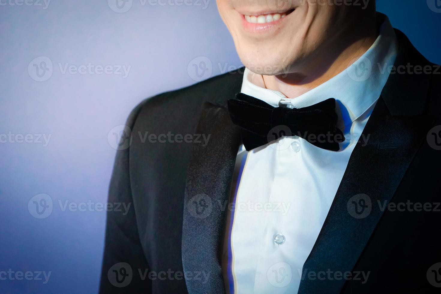 homem inteligente sorrindo em terno de táxi com gravata borboleta no fundo azul violeta claro foto
