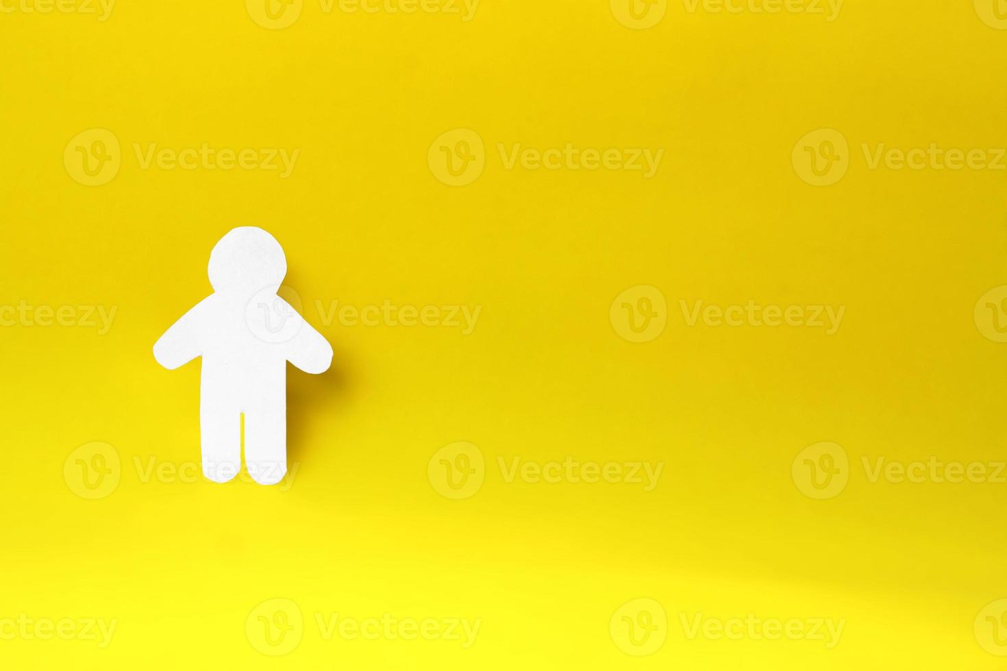 silhueta de um homem de papel branco, cortado à mão. no lado esquerdo da foto em fundo amarelo. com espaço de cópia