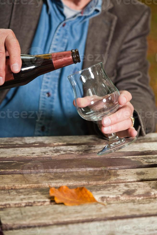 homem sênior desfrutando de cerveja escura ao ar livre na floresta de outono. foto
