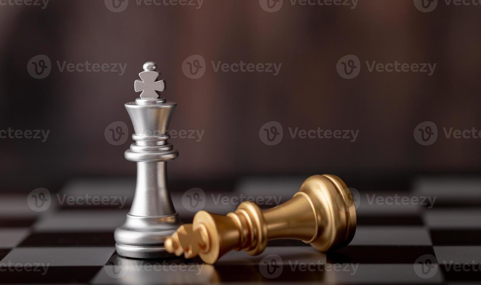rei de prata em pé e ouro caindo no tabuleiro de xadrez foto