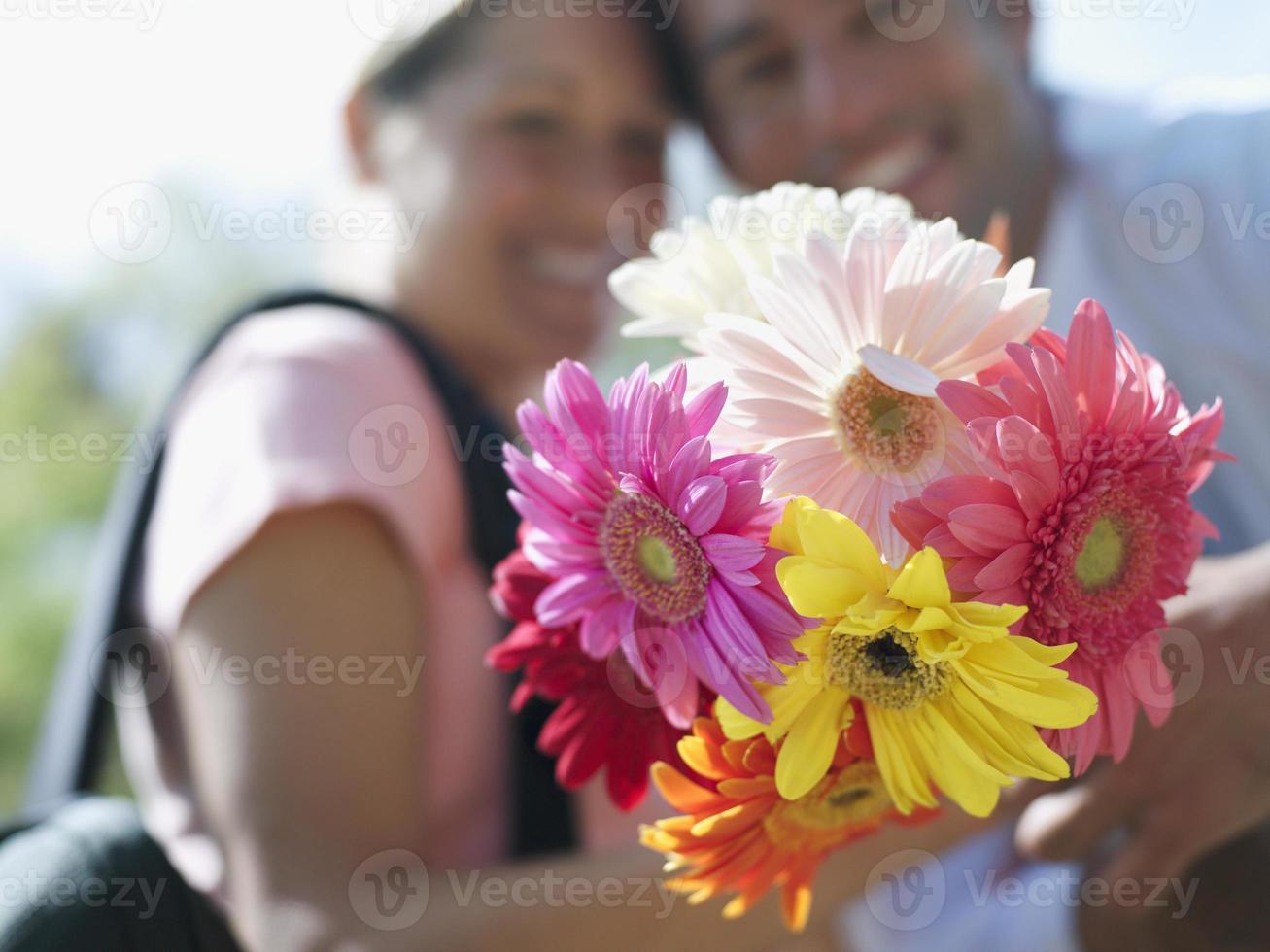 casal segurando ramo de flores coloridas, close-up, foco em fo foto