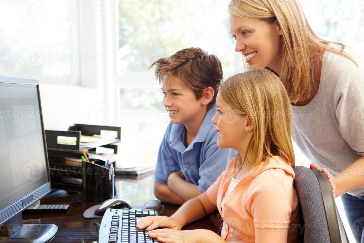 mãe e filhos usando o computador em casa foto
