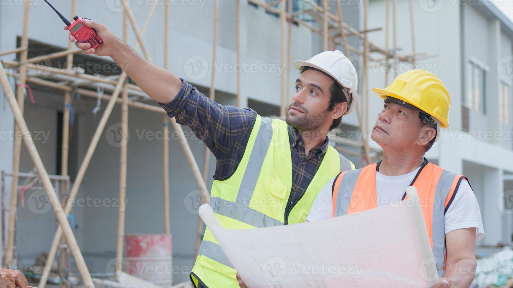 engenheiro civil masculino profissional ou arquiteto, inspetor com empreiteiro, capataz ou trabalhador. enquanto olha para o plano de planta inspecionar discutir o projeto de construção da reunião e apontar no canteiro de obras. foto