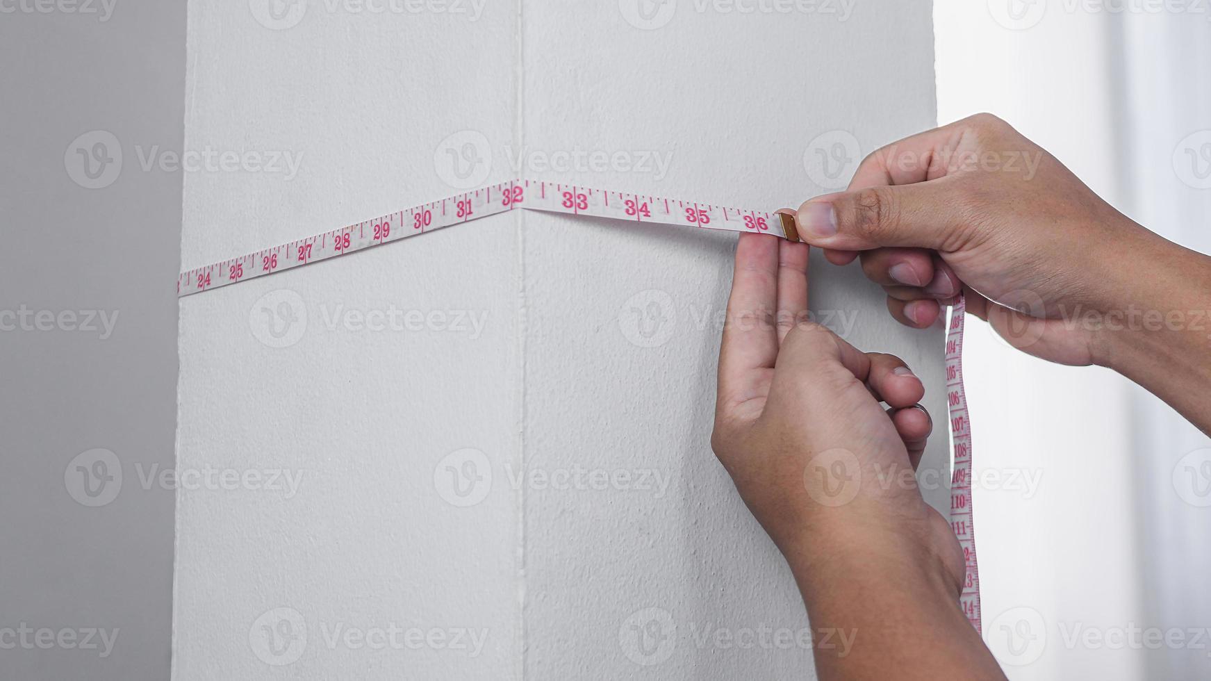 conceito de medição. alguém mede o comprimento do pilar da casa com uma fita na cintura. trabalho diy fácil ou artesanato. foto