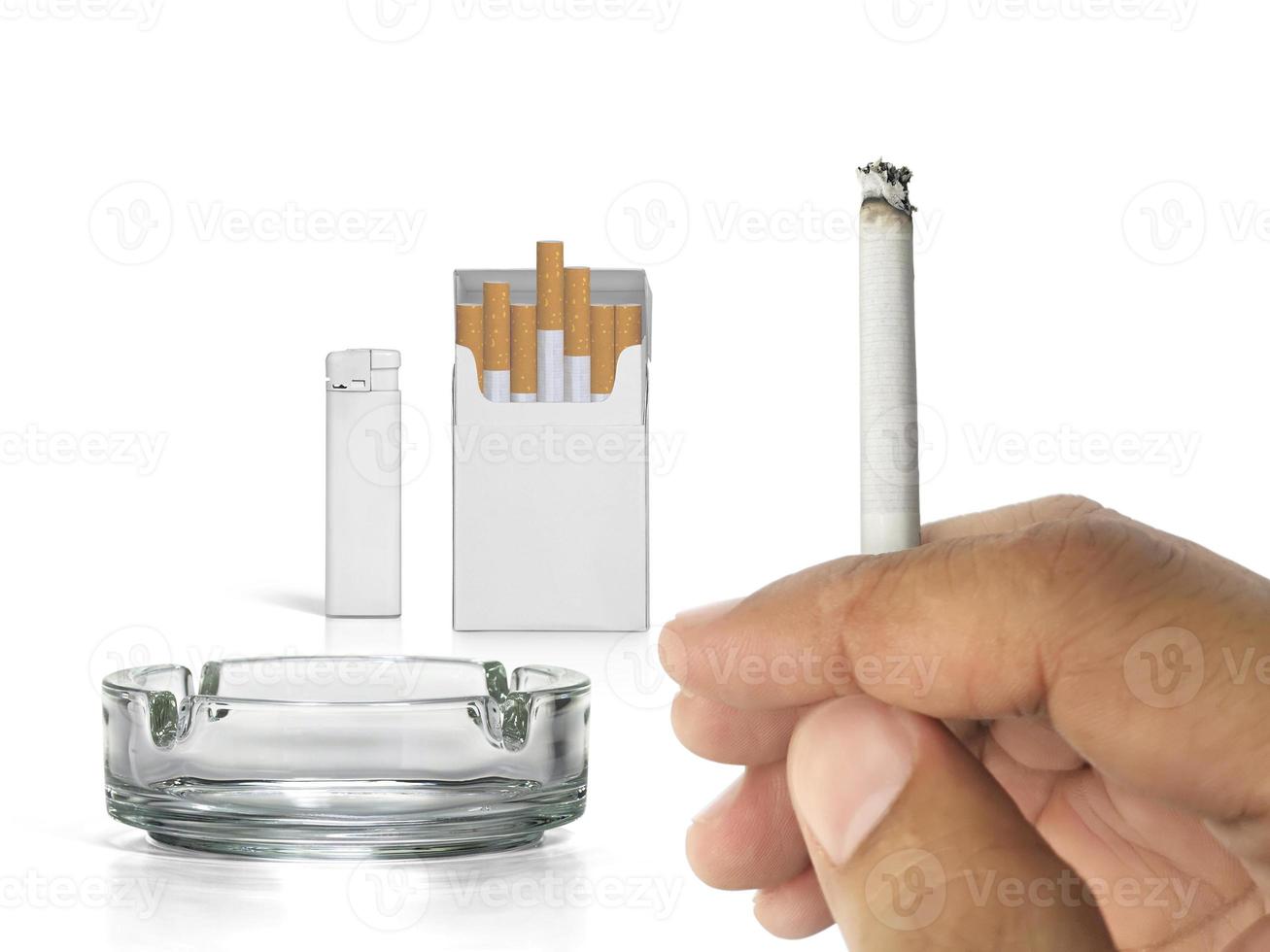 um cigarro na mão, maço de cigarros, cinzeiro e isqueiros isolados no fundo branco foto