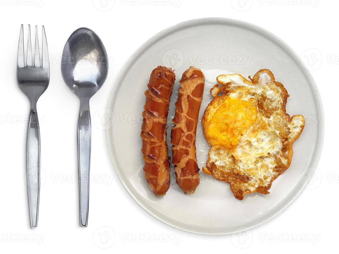 ovo frito em um prato com salsicha de garfo e colher em um fundo branco foto