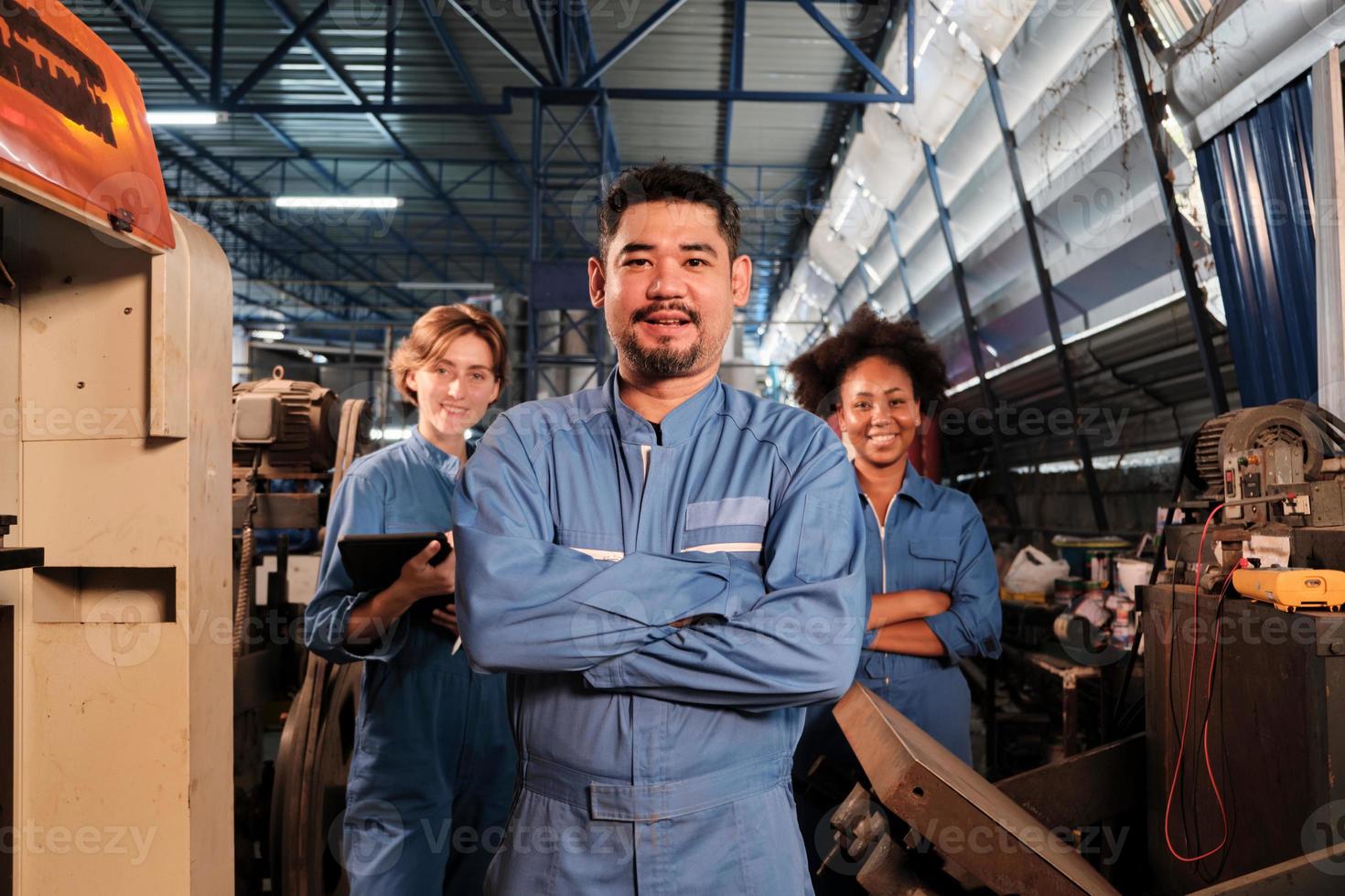 trabalhadores da indústria multirracial em uniformes de segurança colaboram com unidade, braços cruzados e expressam trabalho feliz junto com sorriso e alegre na fábrica mecânica, ocupação profissional de engenheiro. foto