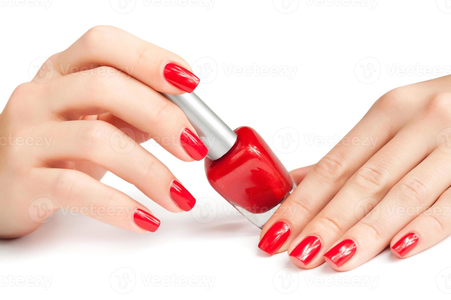 mãos com manicure vermelho e frasco de esmalte isolado foto