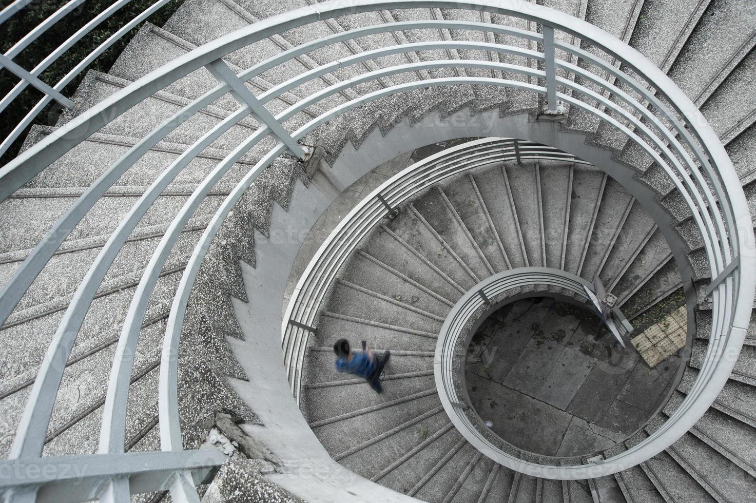 homem de camisa azul, descendo uma escada em espiral foto