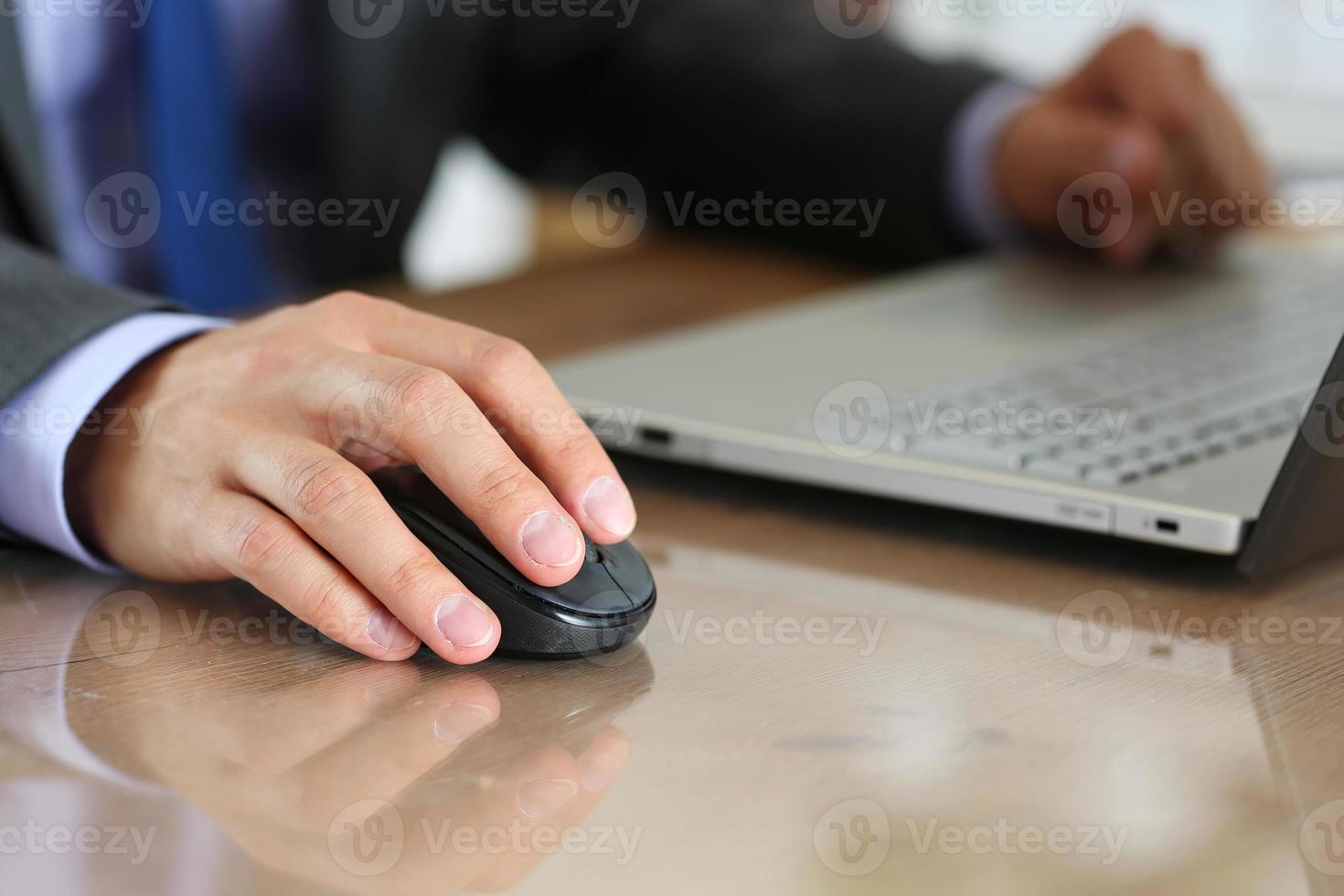 mãos do empresário em terno segurando o mouse sem fio do computador foto