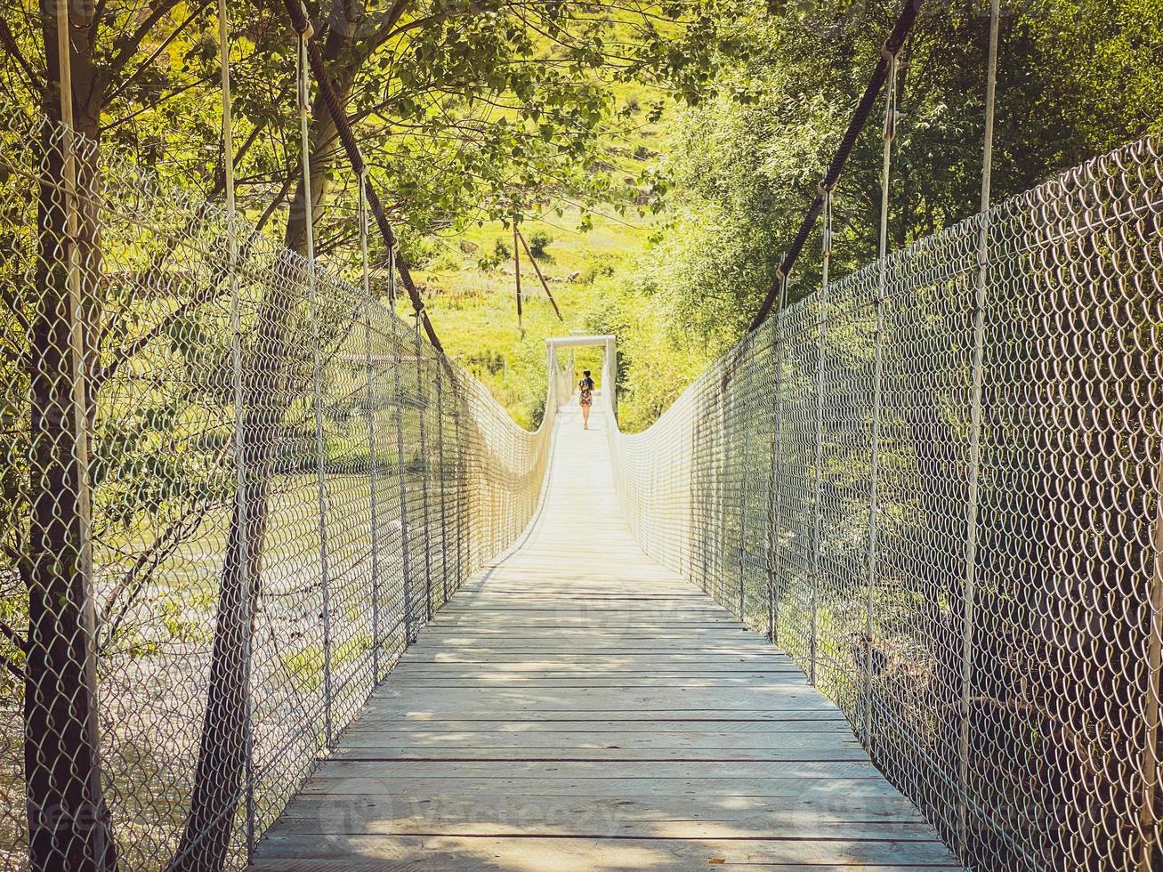 turista feminina anda na ponte de madeira pela fortaleza de khertvisi, passeios na geórgia foto