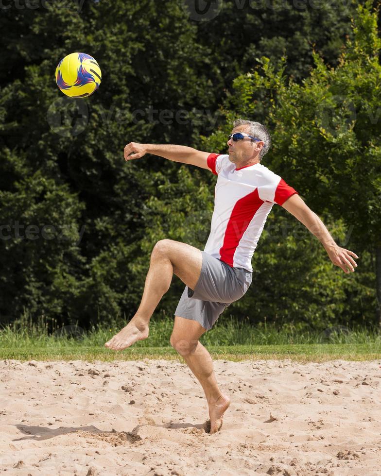 atleta jogando futebol de praia foto