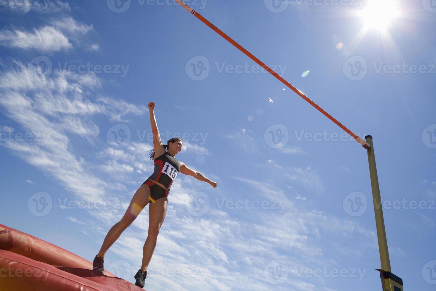 jovem atleta feminina se preparando para pular bar (reflexo de lente) foto