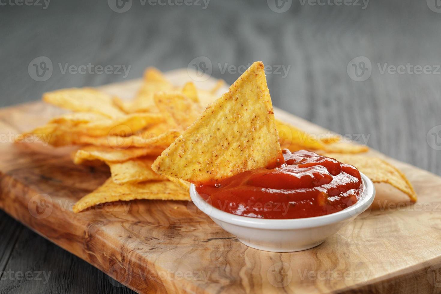pilha de tortilla chips no quadro de azeitona na mesa de madeira foto