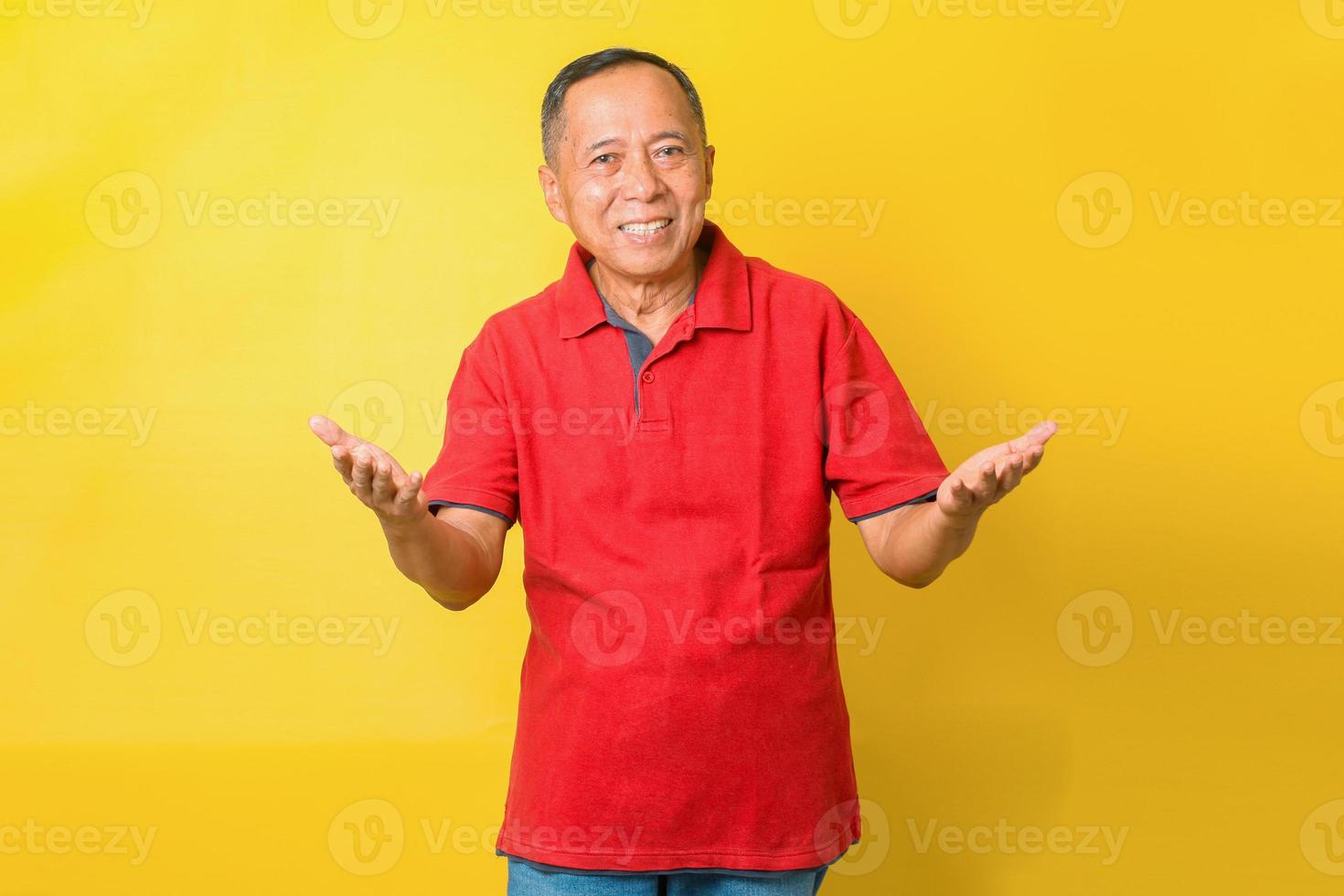 retrato de velho aposentado asiático alegre usa camiseta vermelha está sorrindo e saudando bem-vindo, apontando as mãos ou apresentando. foto