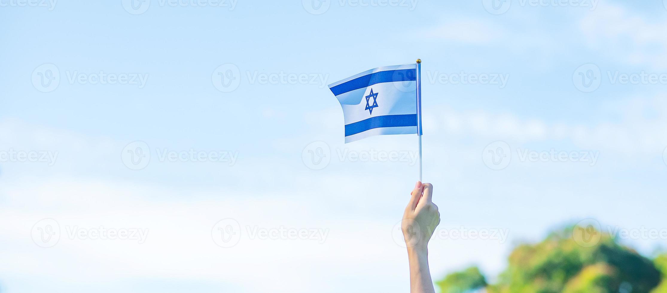 mão segurando a bandeira de israel no fundo da natureza. dia da independência de israel e conceitos de celebração feliz foto