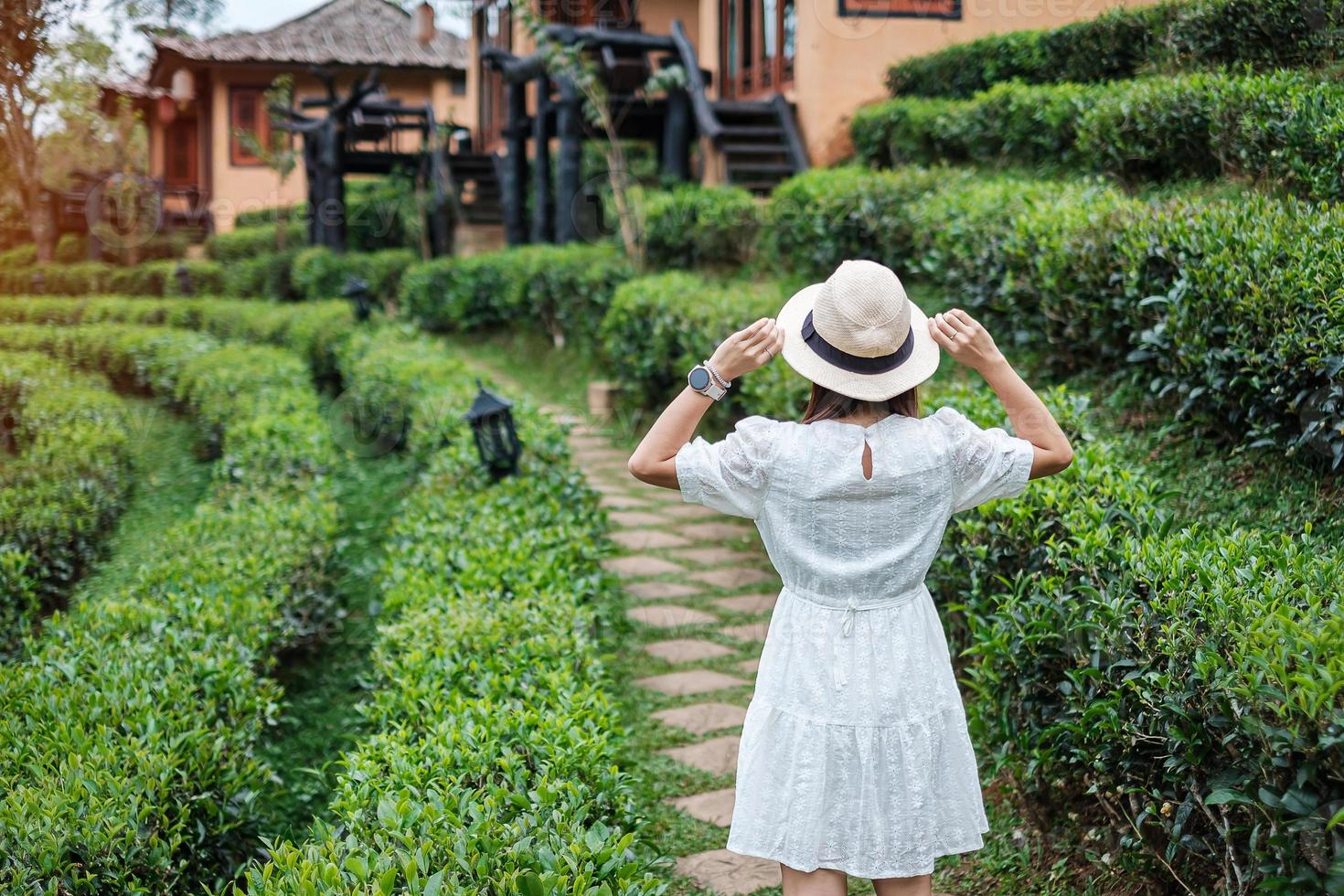 mulher de turista feliz no vestido branco desfrutar de belo chá garden.traveler visitando na vila tailandesa de ban rak, mae hong son, tailândia. conceito de viagens, férias e férias foto