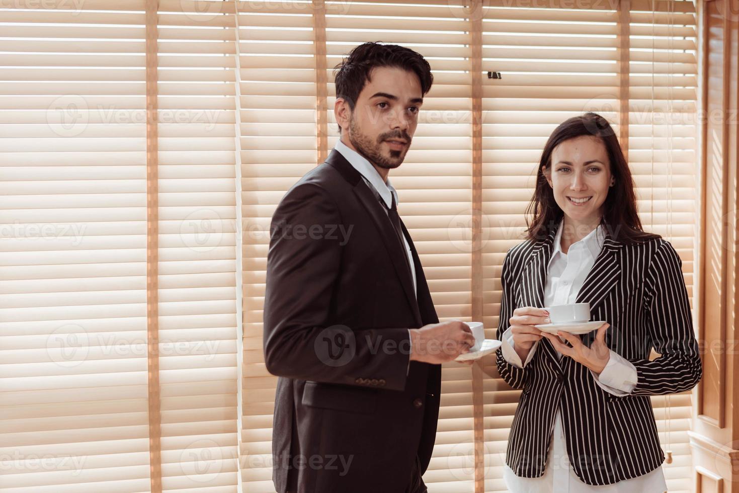 jovem empresário e mulher trabalhando juntos e tomando café no escritório. dois empresários sorrindo e tomando café. negócio e conceito de trabalho. foto