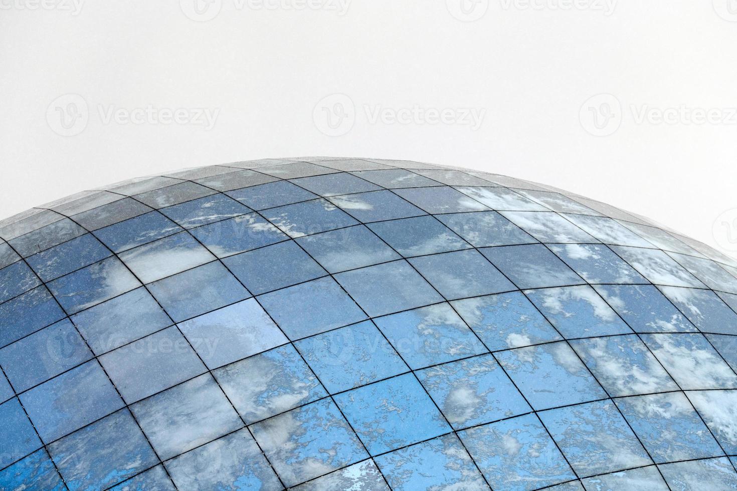 edifício moderno esférico de vidro com reflexo do céu azul foto