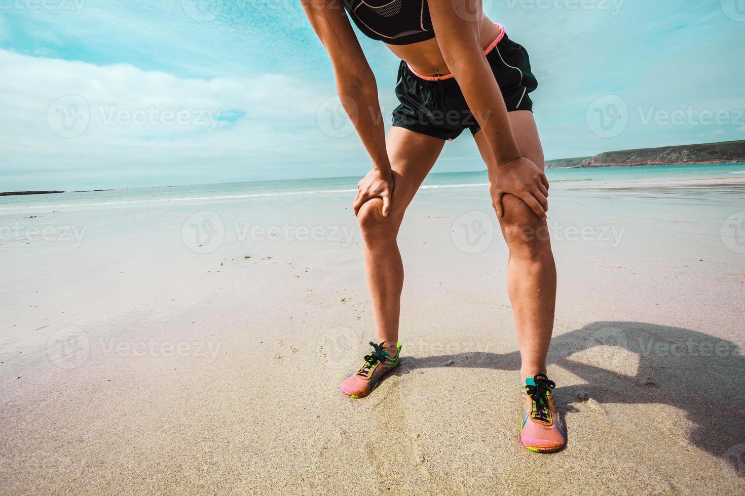 atlética jovem descansando depois de correr na praia foto
