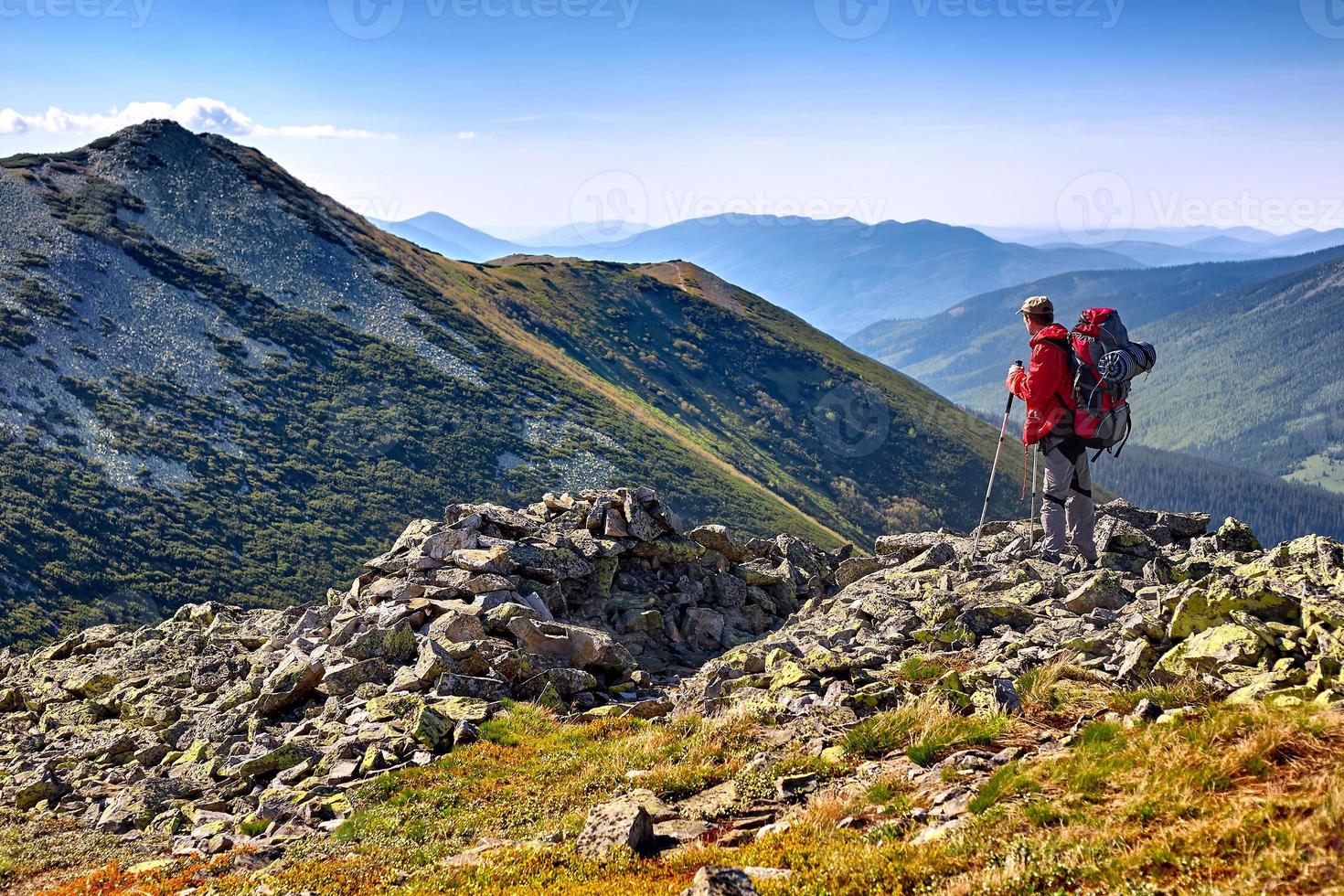 alpinista com mochila em pé nas montanhas e apreciando v foto