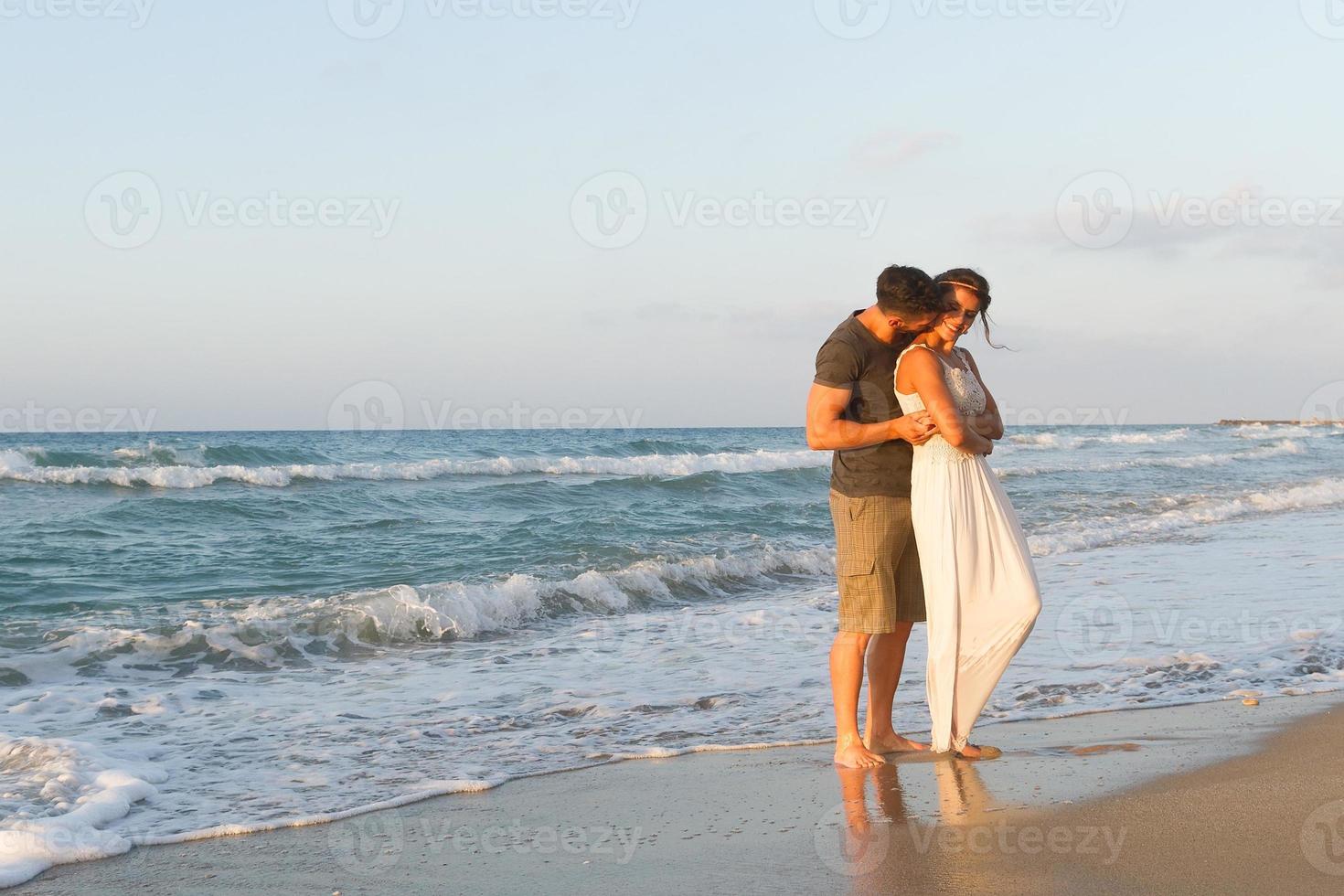 jovem casal gosta de andar em uma praia nebulosa ao entardecer foto