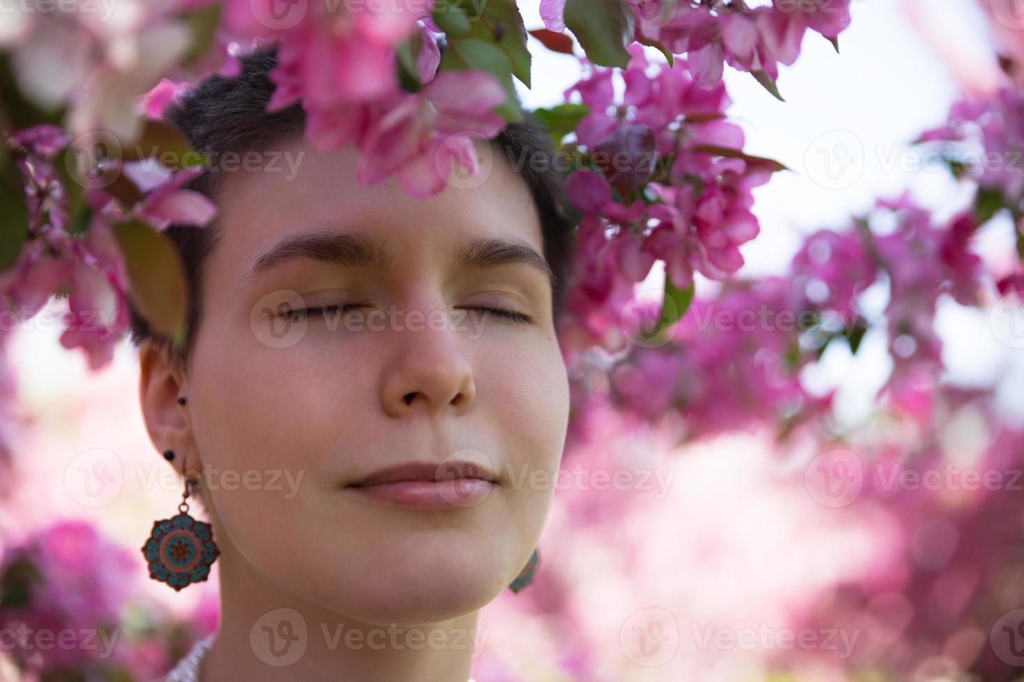menina bonita desfrutar de árvores floridas rosa no verão quente foto