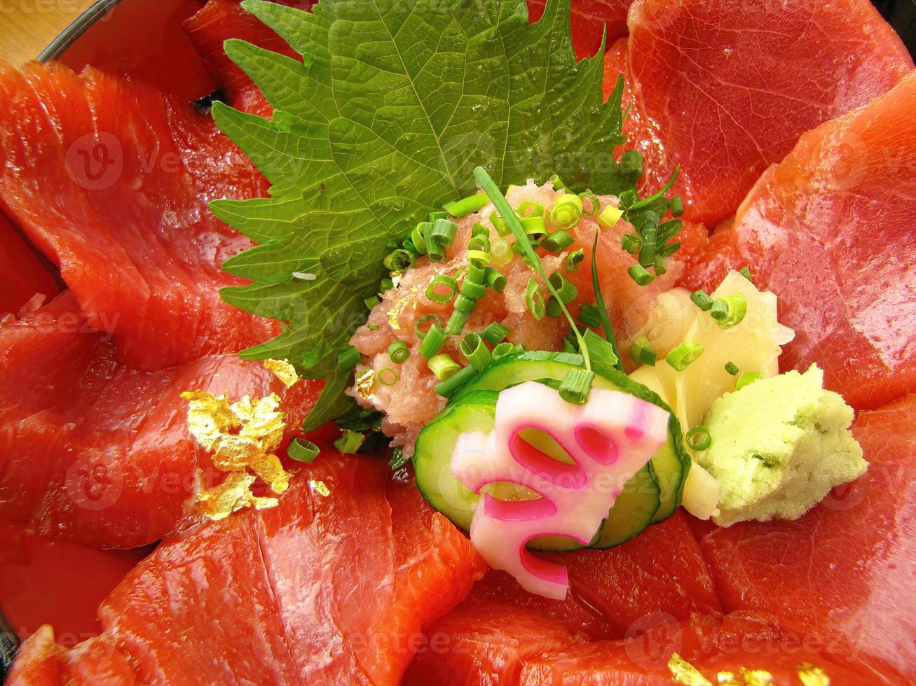 close-up cor vibrante de fatias de atum vermelho frescor no sashimi de arroz japonês don com pepino gengibre e wasabi foto