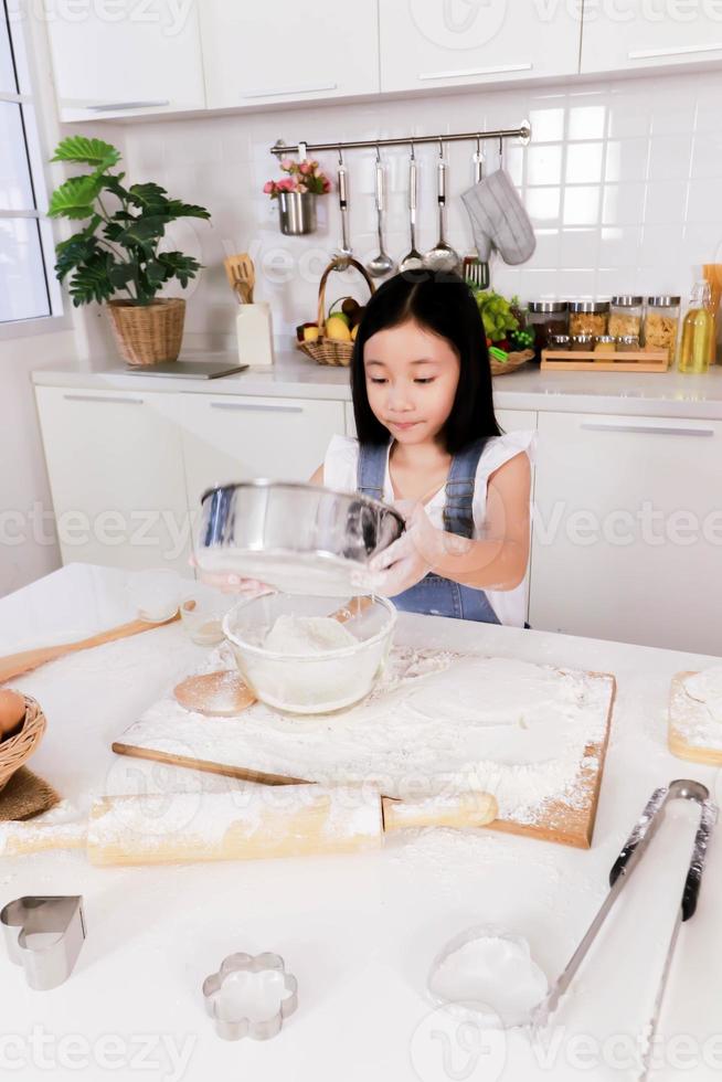 solteiro da irmãzinha peneire a farinha na cozinha foto