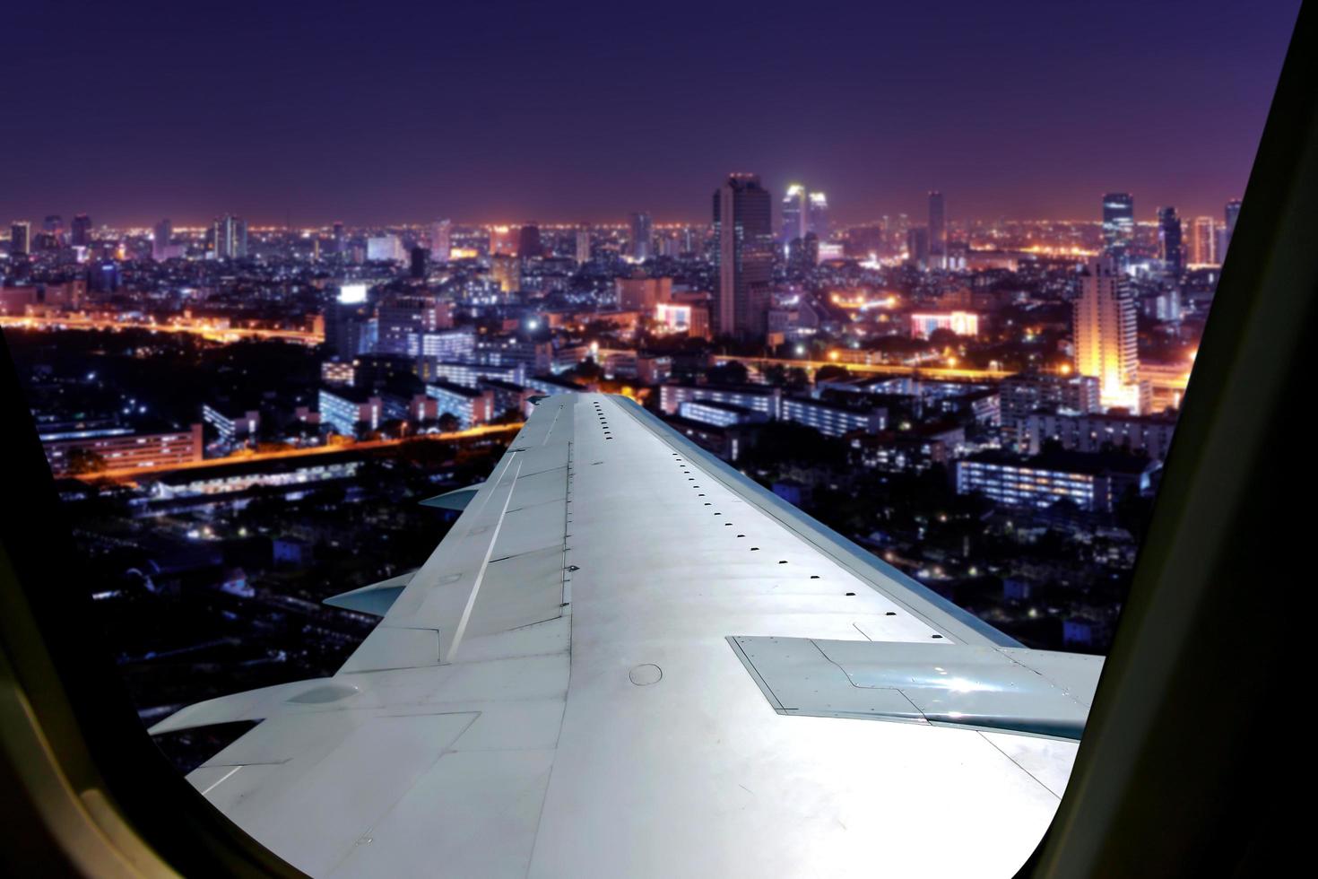 voo noturno no céu crepuscular, vista incrível do avião da janela. assento na janela do avião com vista para a cidade à noite. foto