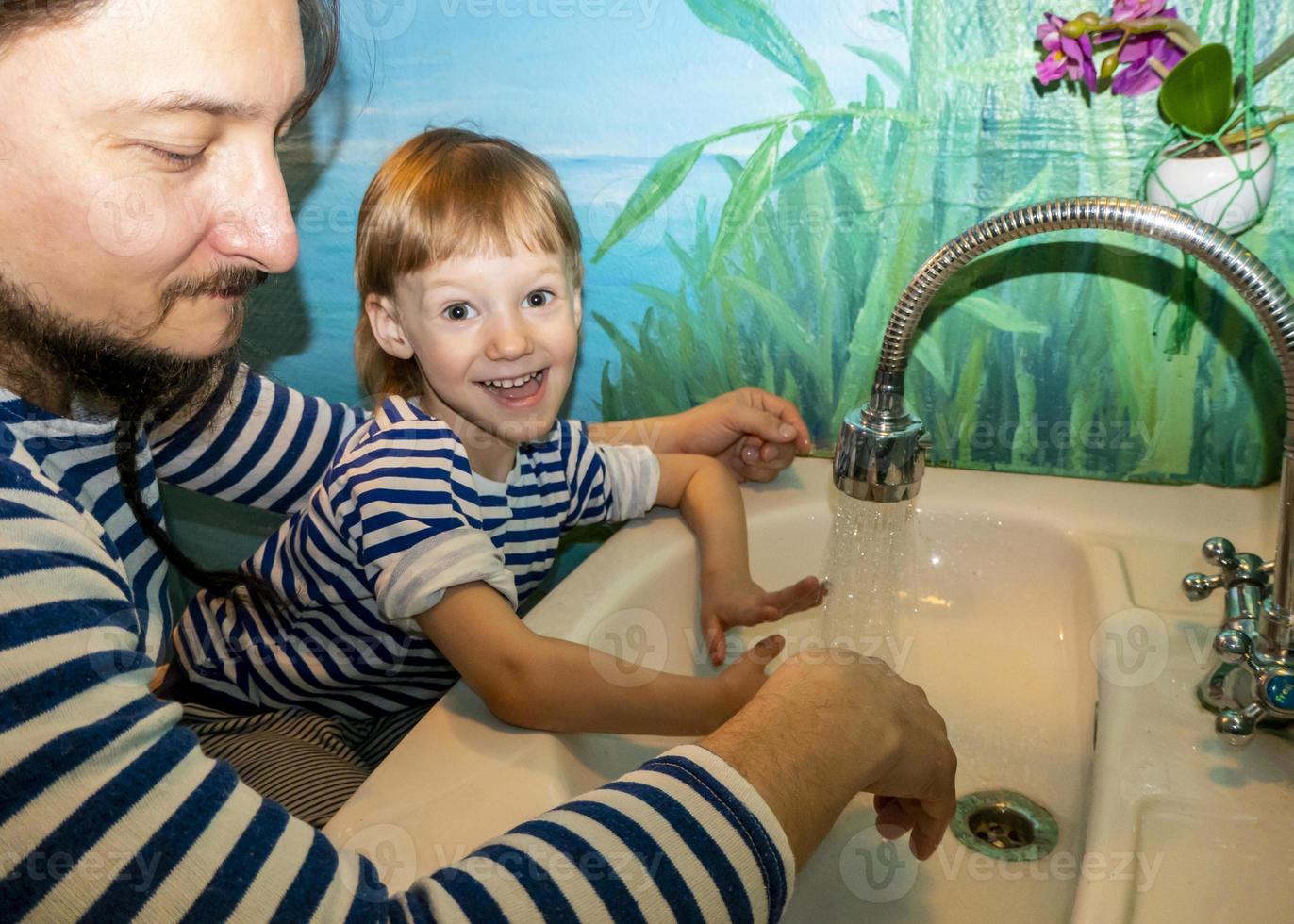 um homem e um menino de colete lavam as mãos foto