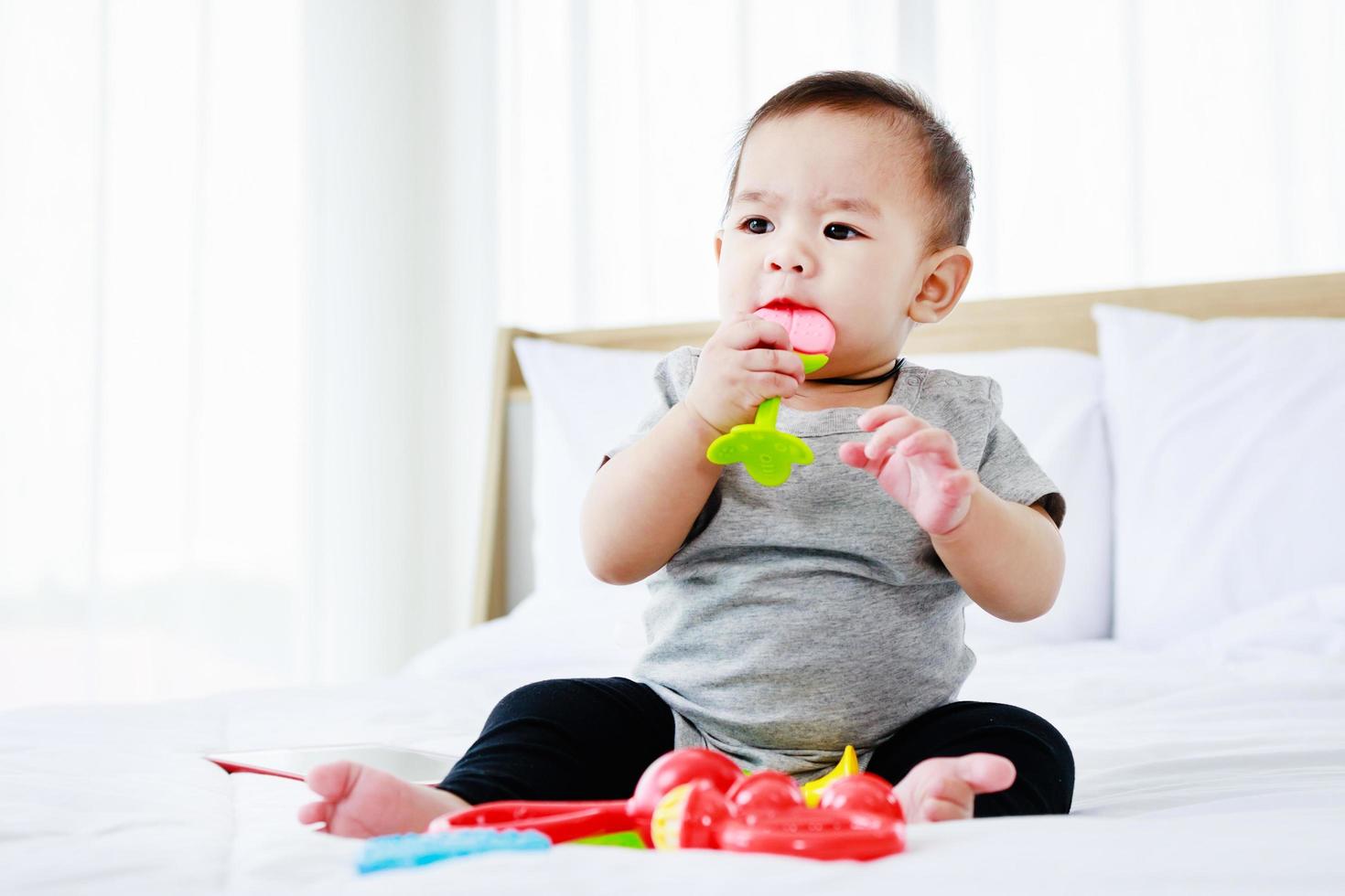 desenvolvimento no conceito de bebê. lindo bebê brincar de brinquedo de bebê na cama. foto