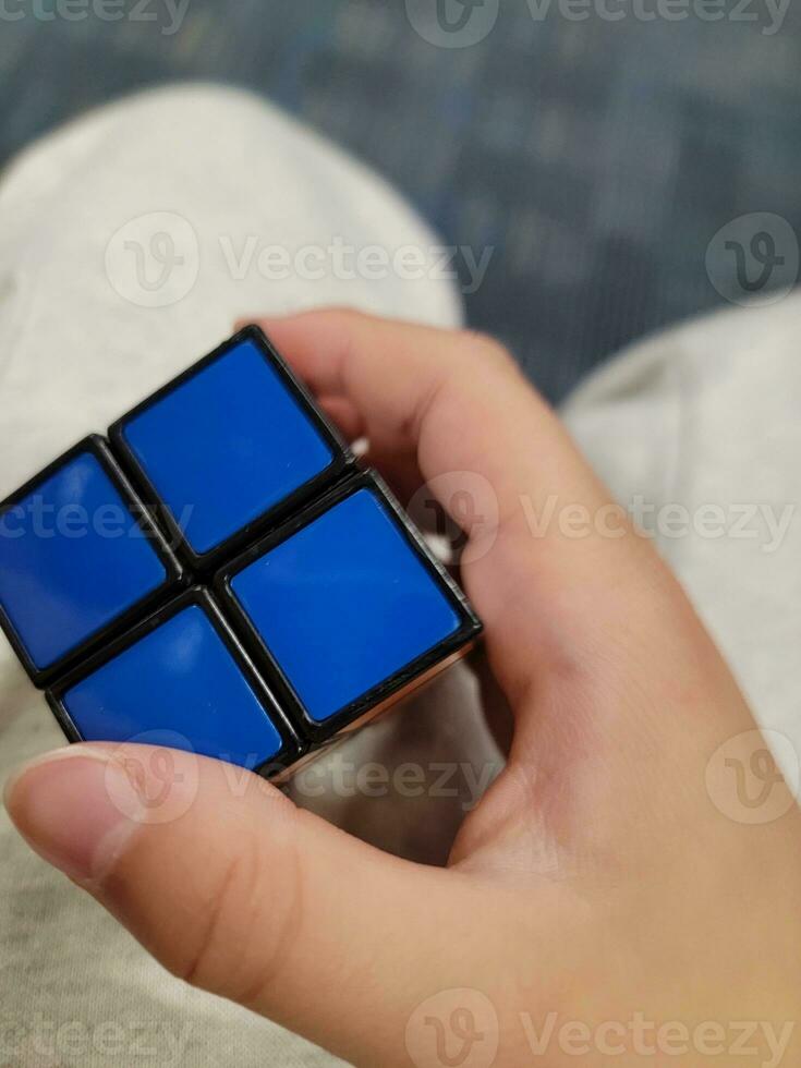 mão de criança segurando o brinquedo cubo com quadrados azuis foto