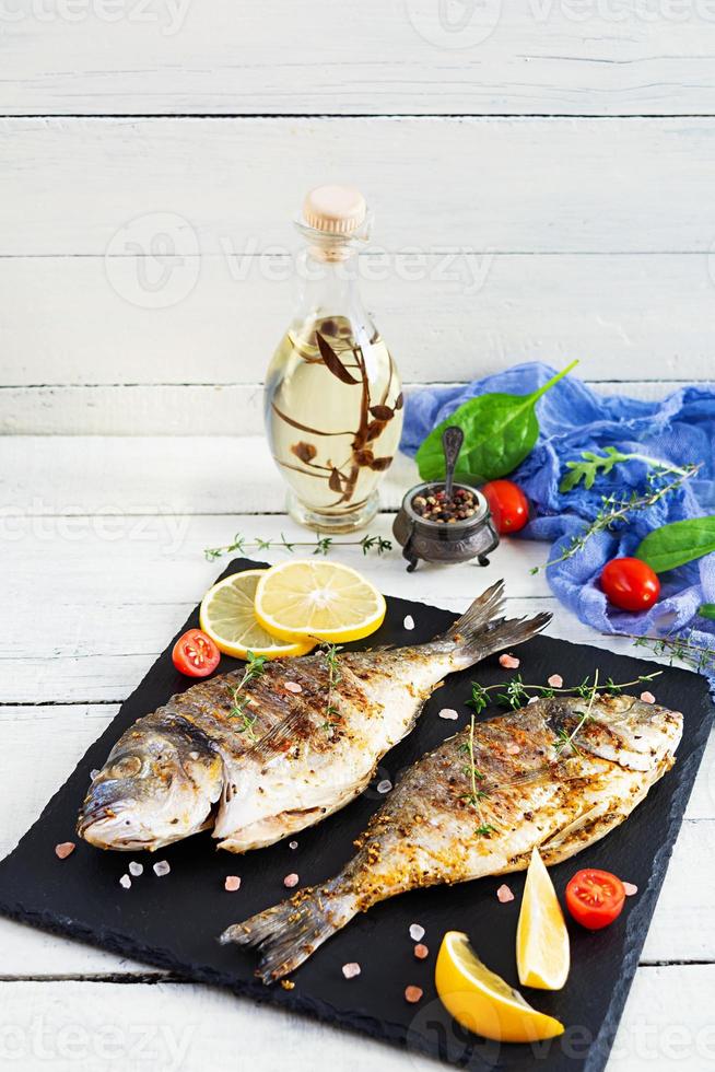 peixe dourado grelhado em fundo de madeira. marisco assado com especiarias e ervas foto