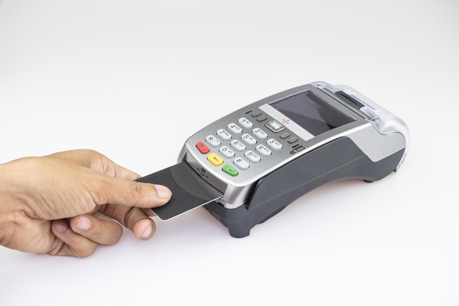 feche a mão do homem usando a máquina de passar cartão de crédito inserindo o código do cartão de crédito para pagar compras on-line no chão da mesa branca foto