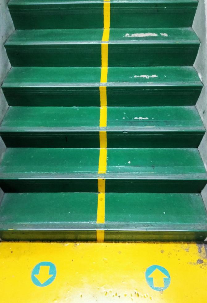 escadas de concreto são pintadas de verde e há setas amarelas indicando o caminho para cima e para baixo, dando ideias, regras. foto