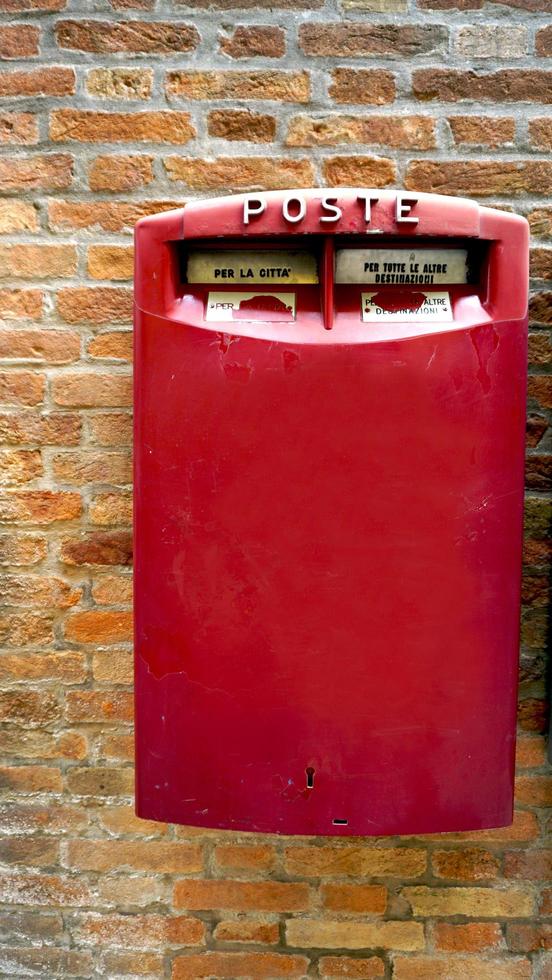 caixa postal vermelha pública na parede de tijolos foto