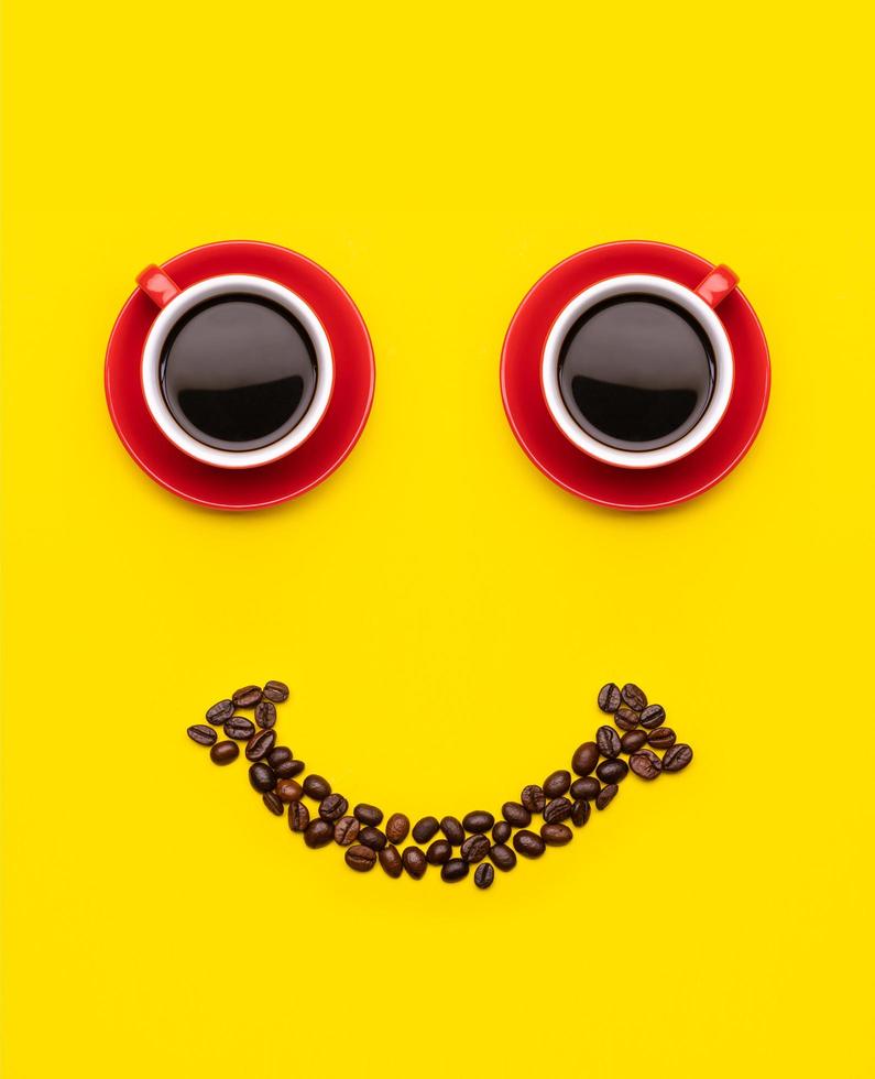 xícara de café e grãos de café com conceito de rosto de sorriso, vista superior sobre fundo amarelo. para o conceito feliz de manhã foto