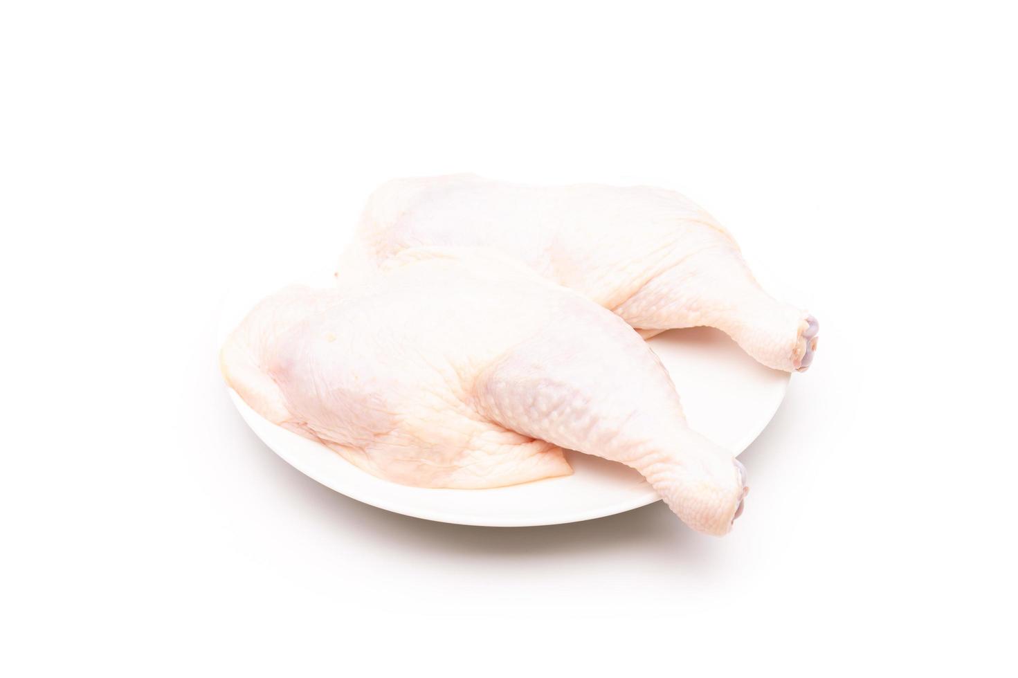 coxas de frango cru em prato branco isolado no branco foto