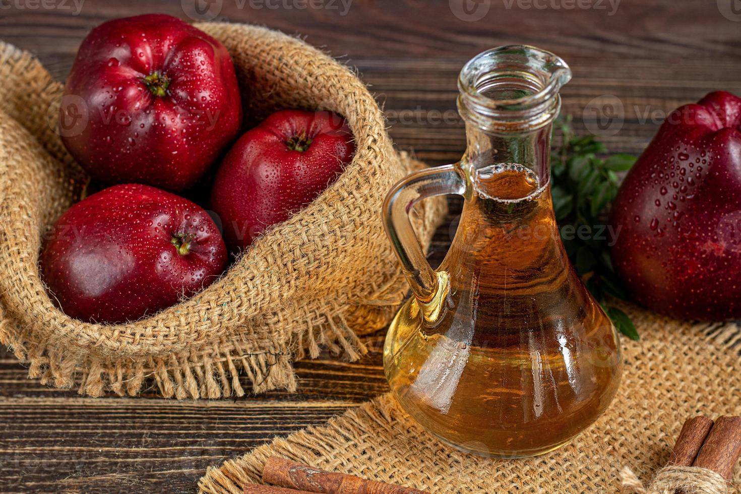 vinagre de maçã e maçãs vermelhas em um fundo escuro de madeira. foco seletivo. produto fermentado. comida saudável. foto