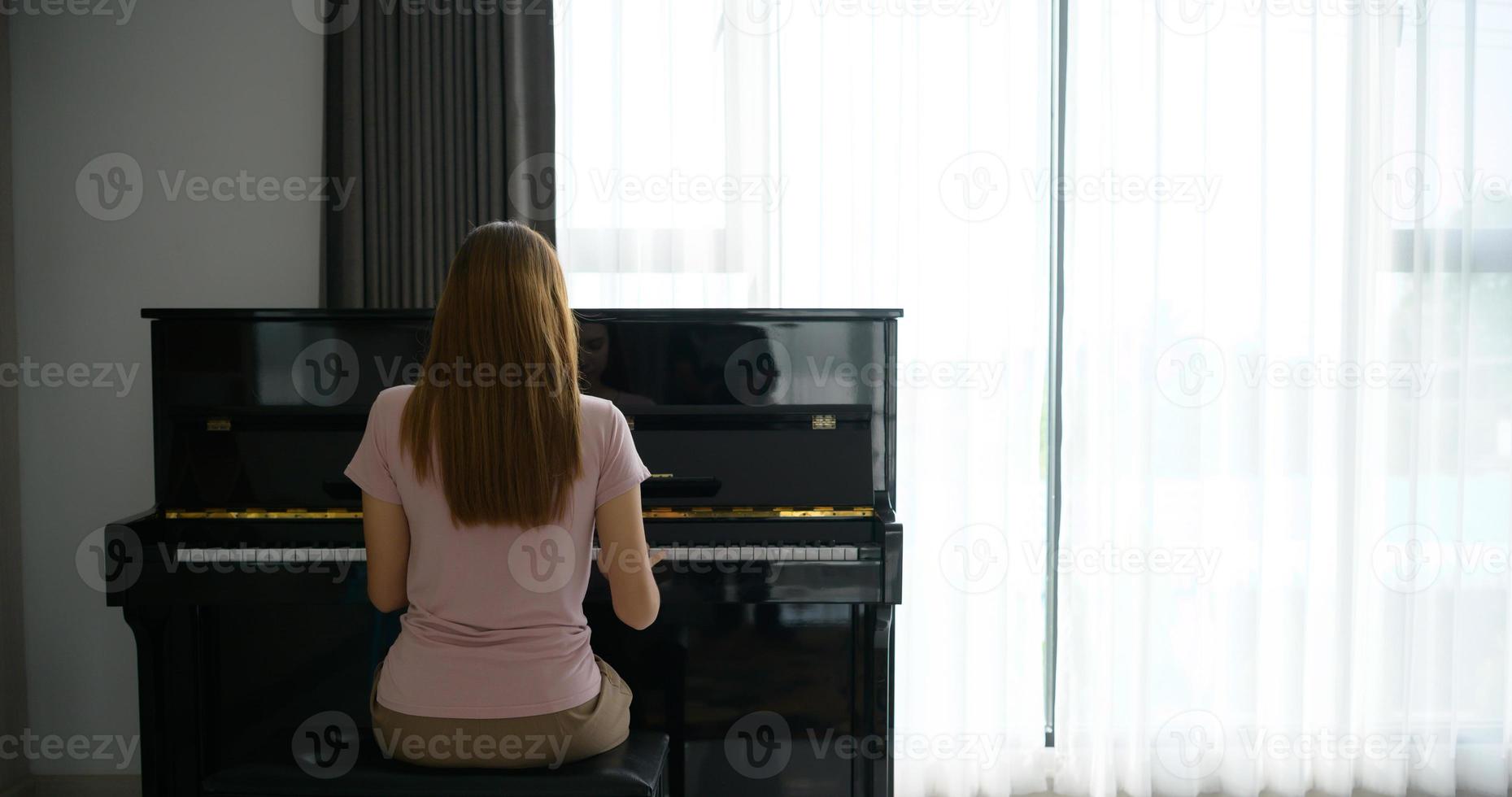 menina asiática tocando piano em uma manhã ensolarada. foto