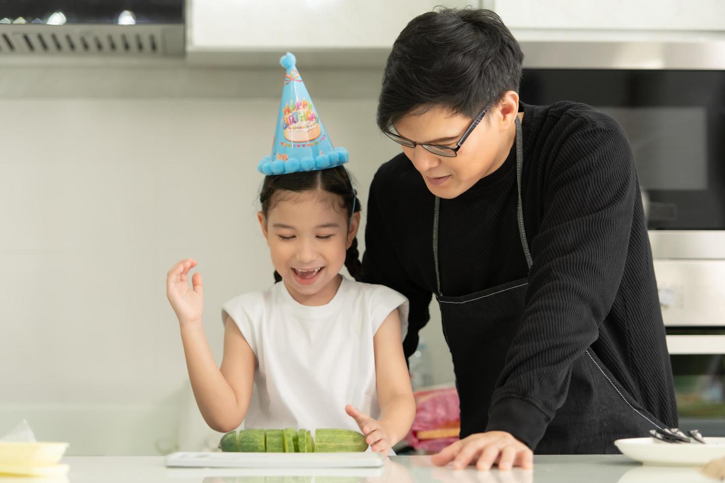 família asiática de nova geração cozinha junta e organiza uma pequena festa de aniversário para nossa filhinha na cozinha da casa foto