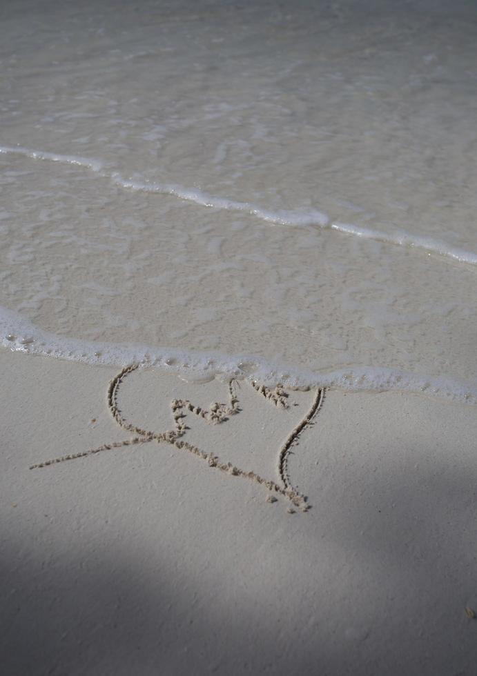 corações desenhados na areia de uma praia foto