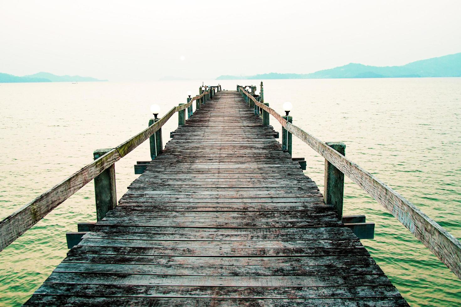 uma passarela de madeira que se estende até o mar. conceito de viagem de férias foto