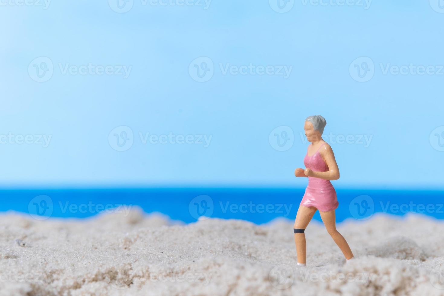 pessoas em miniatura correndo na praia foto